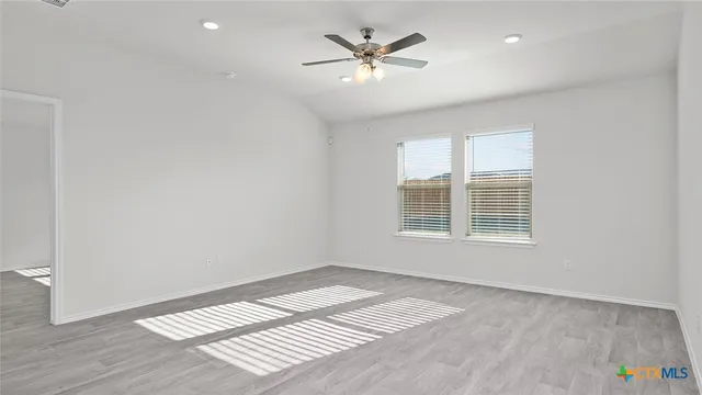 an empty room with a window and a ceiling fan