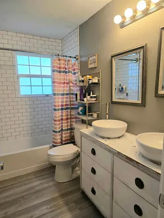 a bathroom with a granite countertop sink a toilet a mirror and shower
