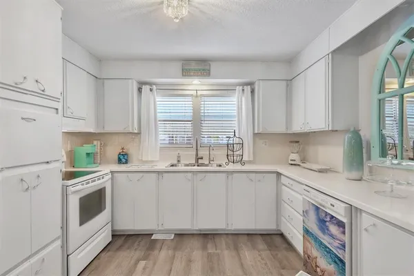 a kitchen with granite countertop white cabinets a sink a window and appliances