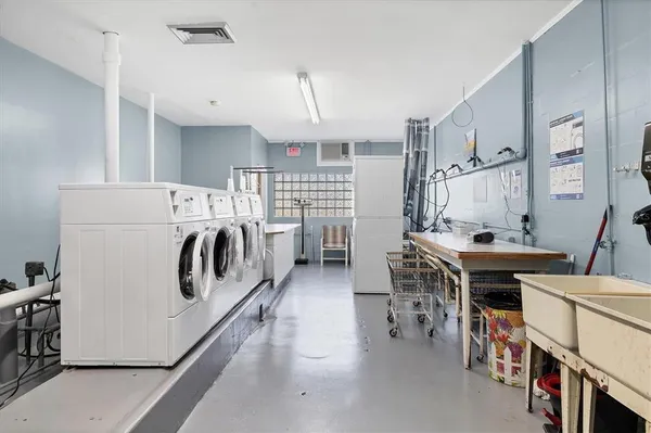 a kitchen with stainless steel appliances a white stove top oven a sink dishwasher and a dining table with white cabinets