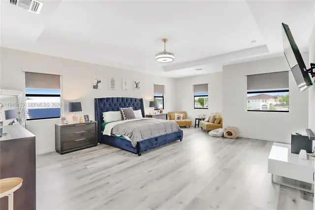 a spacious bedroom with a bed and a flat screen tv