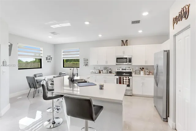 a living room with furniture a refrigerator and a kitchen view