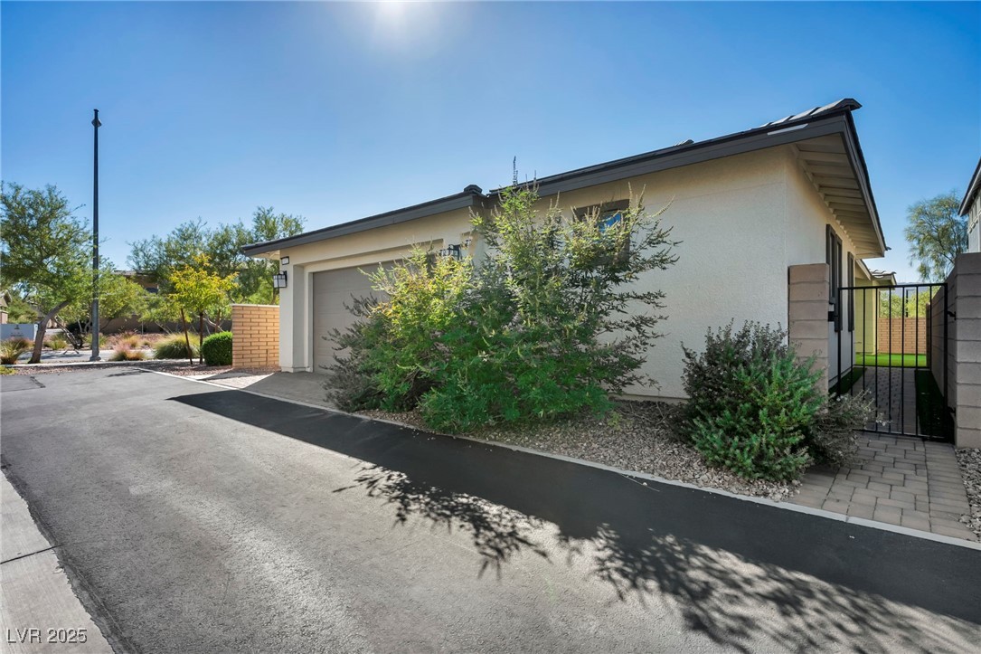 1012 East Sunset Road Henderson, NV 89011 - Photo 17 of 77 View of home's exterior featuring stucco siding, an attached garage, and a gate