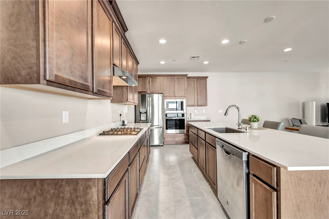1012 East Sunset Road Henderson, NV 89011 - Photo 50 of 77 Kitchen featuring stainless steel appliances, recessed lighting, a kitchen island with sink, light tile patterned flooring, and under cabinet range hood