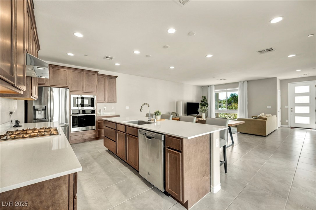 1012 East Sunset Road Henderson, NV 89011 - Photo 76 of 77 Kitchen featuring recessed lighting, appliances with stainless steel finishes, a kitchen island with sink, a breakfast bar, and open floor plan