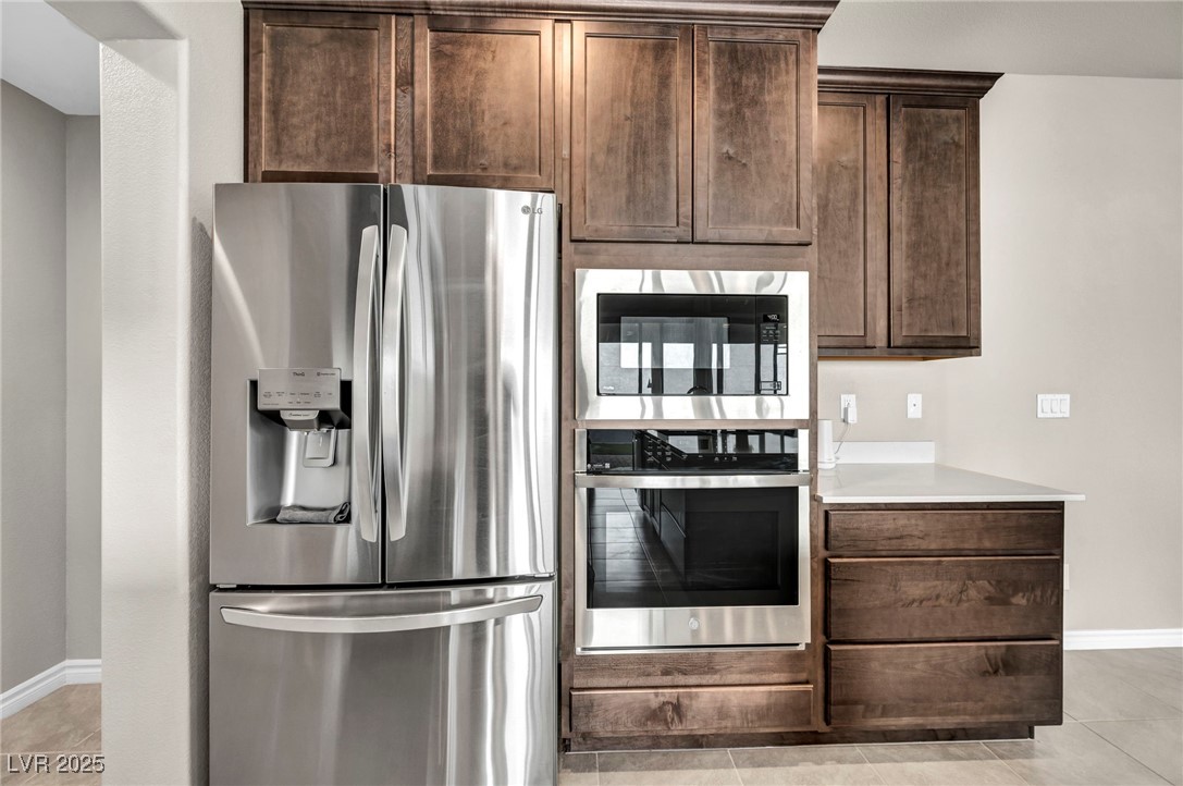 1012 East Sunset Road Henderson, NV 89011 - Photo 51 of 77 Kitchen featuring stainless steel appliances, light tile patterned floors, and dark brown cabinetry