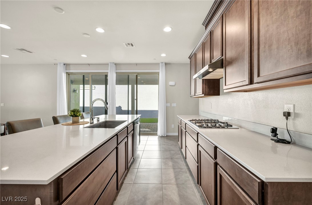 1012 East Sunset Road Henderson, NV 89011 - Photo 52 of 77 Kitchen with dark brown cabinetry, a large island, recessed lighting, and light stone countertops