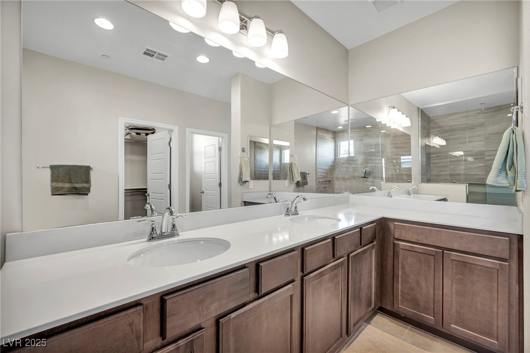 1012 East Sunset Road Henderson, NV 89011 - Photo 60 of 77 Full bathroom with double vanity, recessed lighting, tiled shower, light tile patterned flooring, and a walk in closet