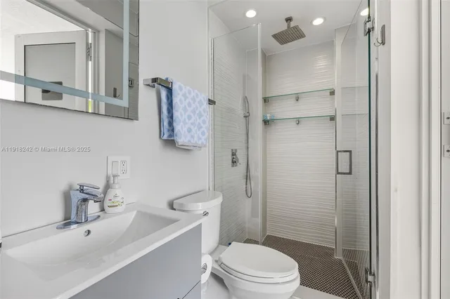 a kitchen with stainless steel appliances kitchen island granite countertop a refrigerator a oven a sink and white cabinets with wooden floor