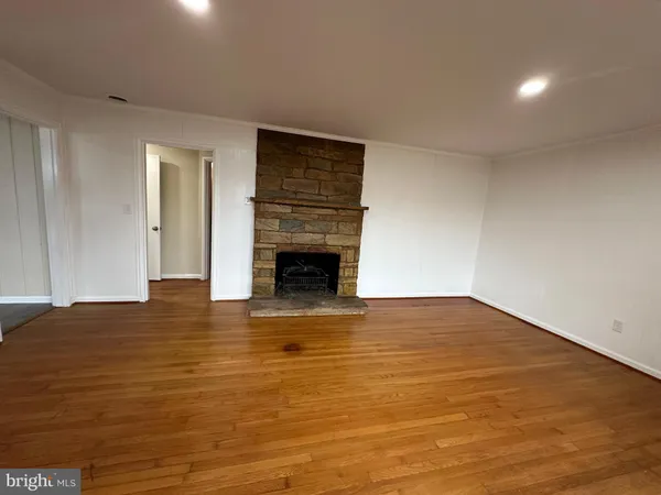 a view of empty room with wooden floor and fireplace