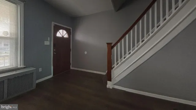 an entryway in a hall with wooden floor and a window