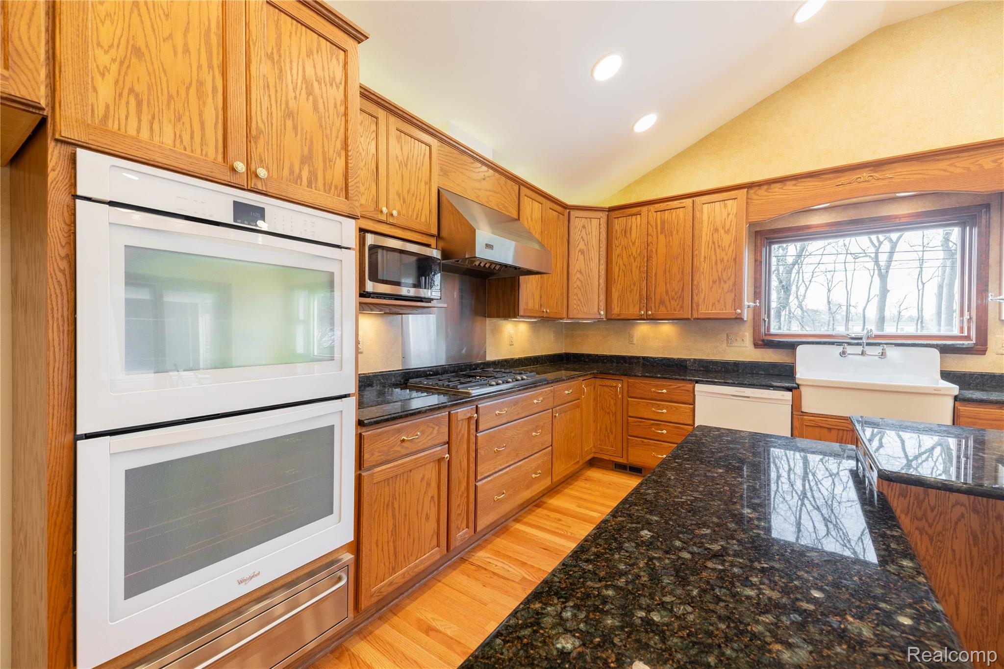 7611 Ferry Road Grosse Ile, MI 48138 - Photo 15 of 51 Kitchen featuring wood cabinetry, dark granite countertops, built-in double ovens, stainless steel appliances, and a farmhouse sink