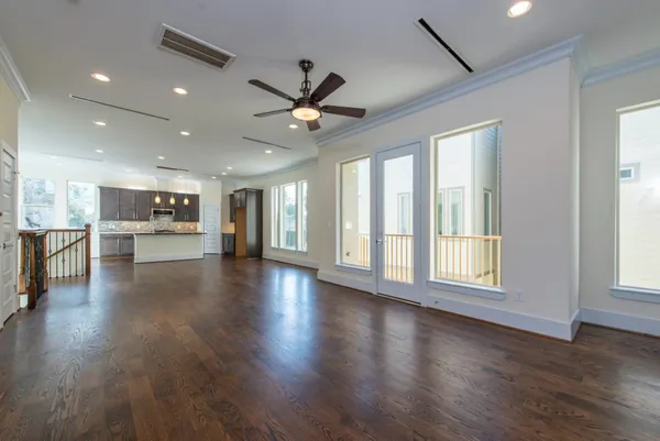 a view of an empty room with a kitchen and wooden floor