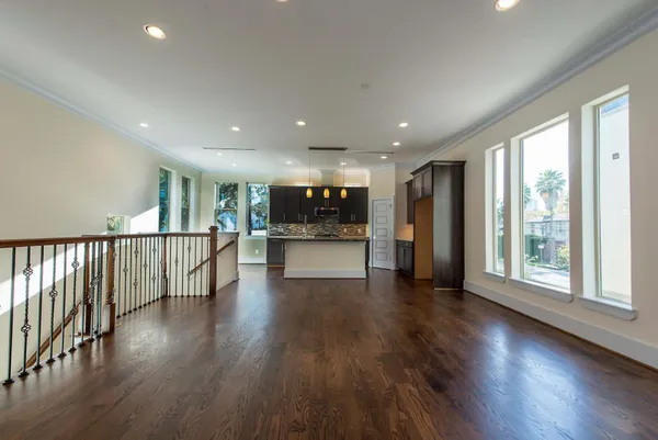 a view of an empty room with wooden floor and windows