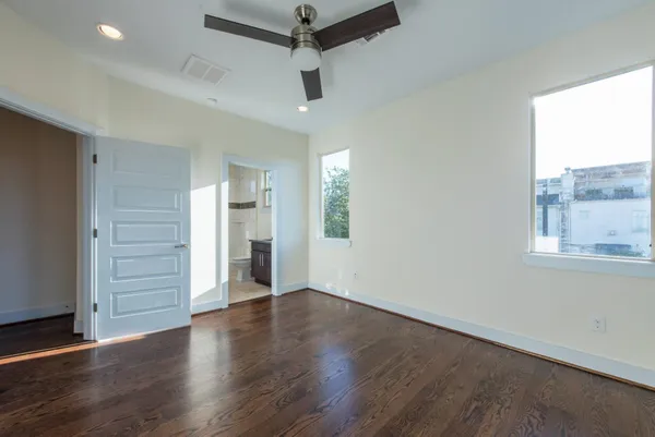 an empty room with wooden floor cabinet and windows