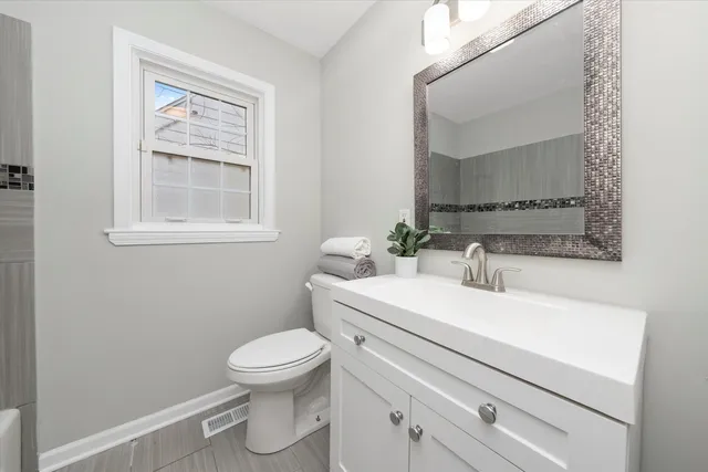 a bathroom with a toilet sink vanity and mirror