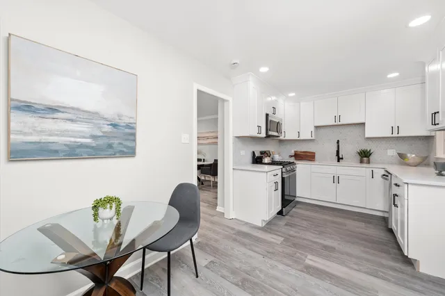 a kitchen with a dining table chairs and wooden floor