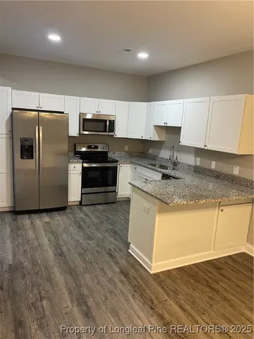 a kitchen with granite countertop a refrigerator and a stove top oven