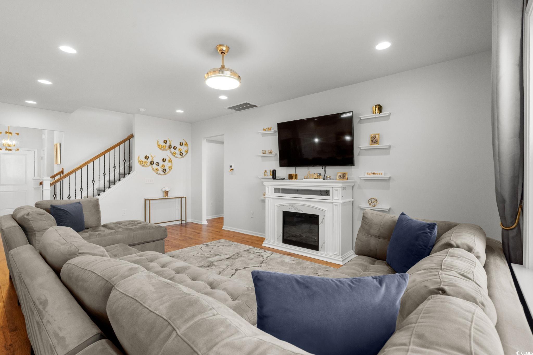 1663 Villena Drive Myrtle Beach, SC 29579 - Photo 10 of 40 Living area featuring wood finished floors, recessed lighting, a glass covered fireplace, stairs, and a chandelier