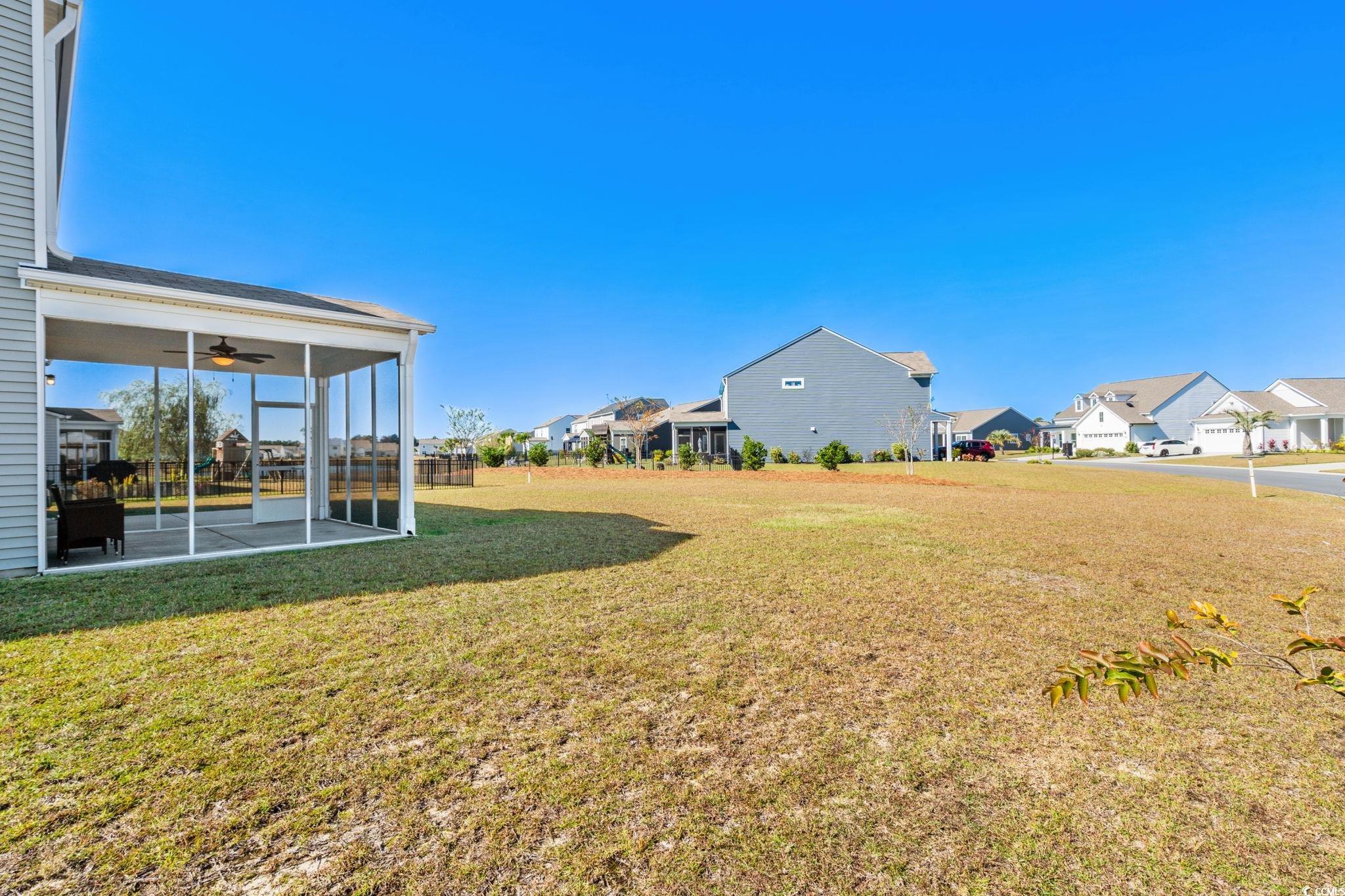 1663 Villena Drive Myrtle Beach, SC 29579 - Photo 33 of 40 View of green lawn featuring a ceiling fan, a sunroom, and a residential view