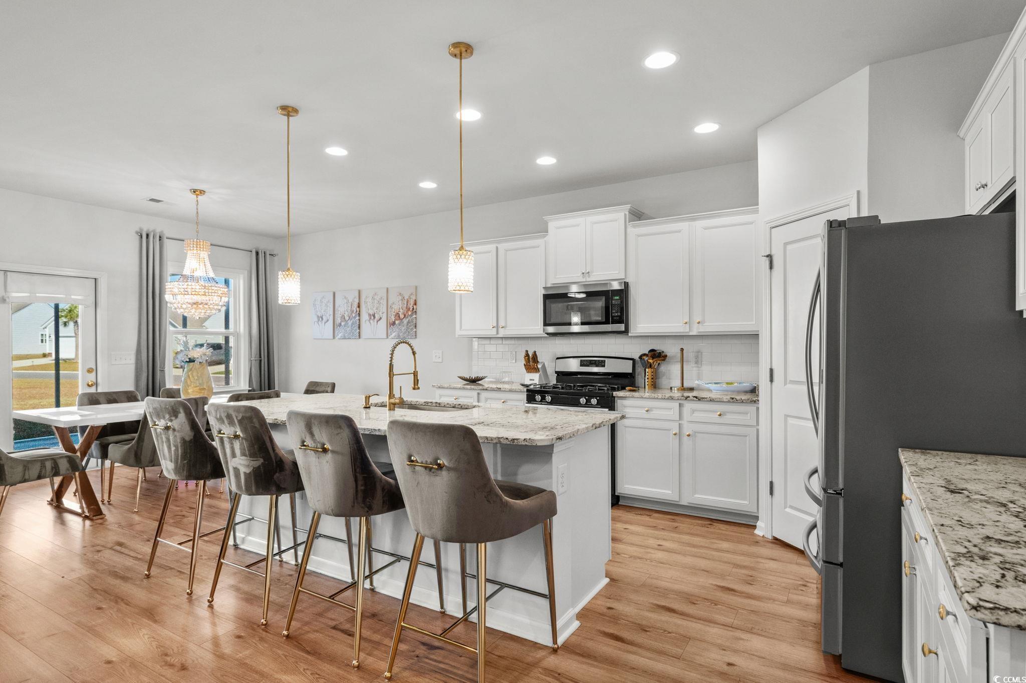 1663 Villena Drive Myrtle Beach, SC 29579 - Photo 5 of 40 Kitchen with a breakfast bar area, decorative backsplash, stainless steel appliances, hanging light fixtures, and a kitchen island with sink