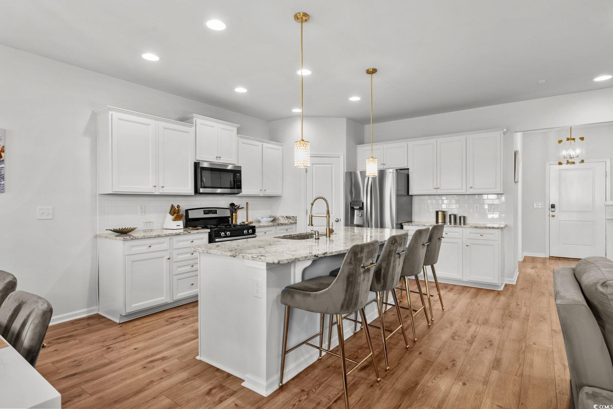 1663 Villena Drive Myrtle Beach, SC 29579 - Photo 8 of 40 Kitchen featuring decorative backsplash, a kitchen bar, white cabinets, stainless steel appliances, and recessed lighting