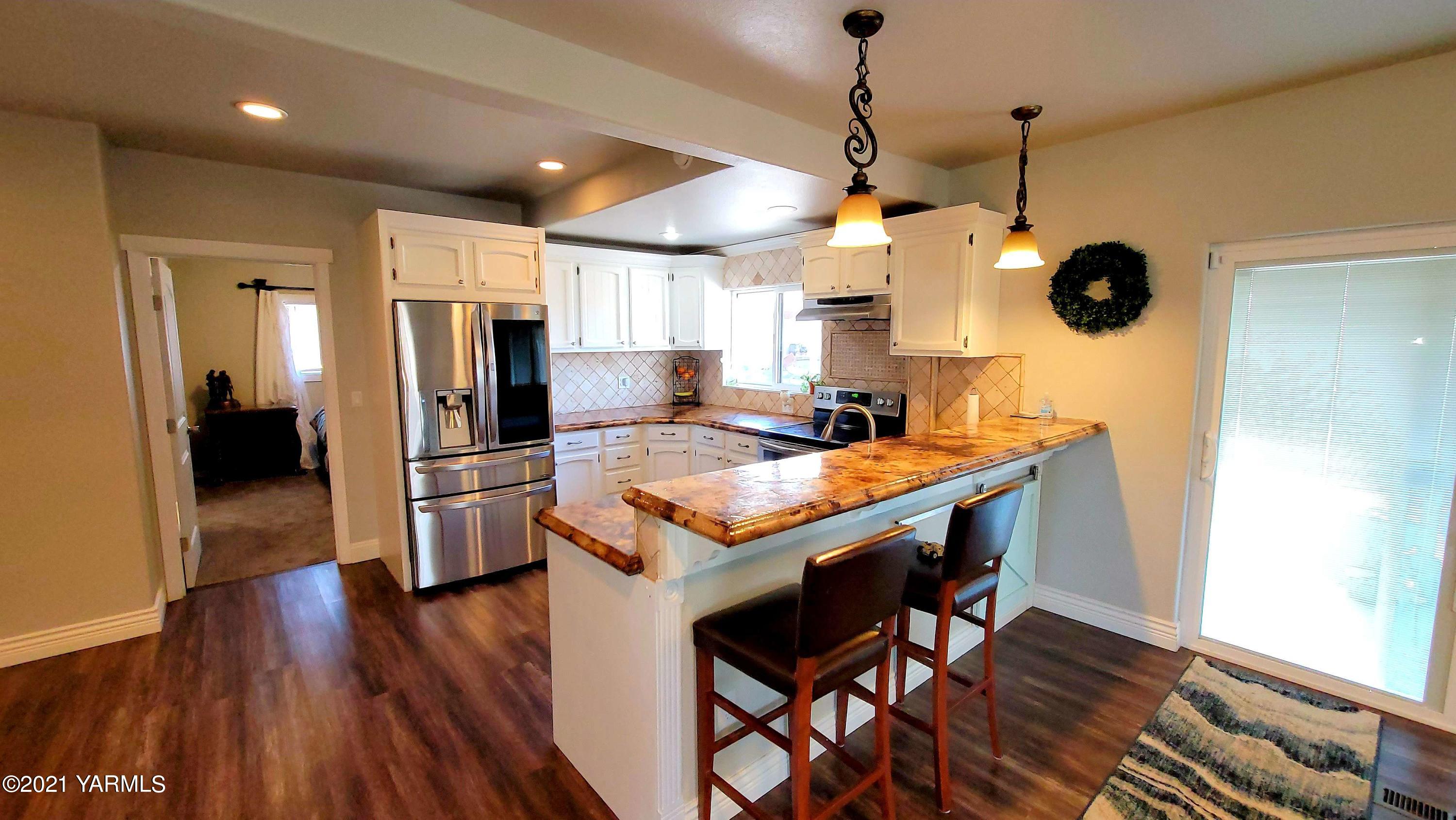 1141 Alexander Road Sunnyside, WA 98944 - Photo 6 of 16 a kitchen with stainless steel appliances kitchen island granite countertop wooden floors and a view of living room