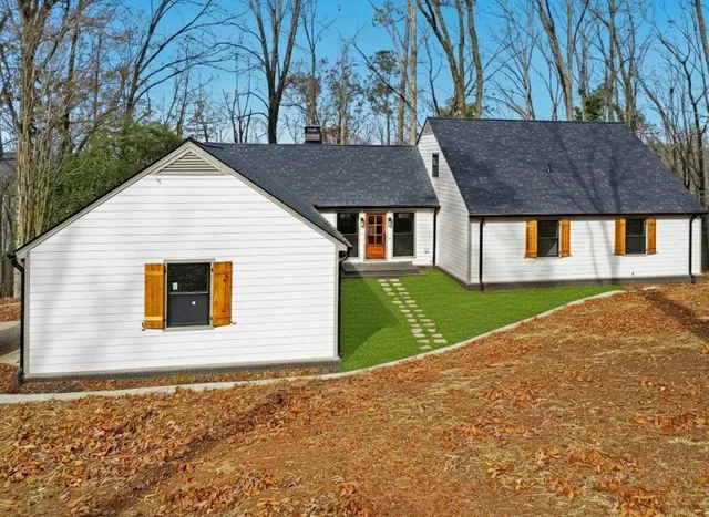 a view of house with yard and trees in the background