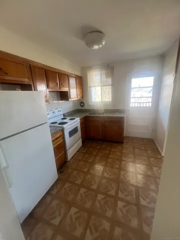 a room with kitchen island a sink a stove a refrigerator and cabinets