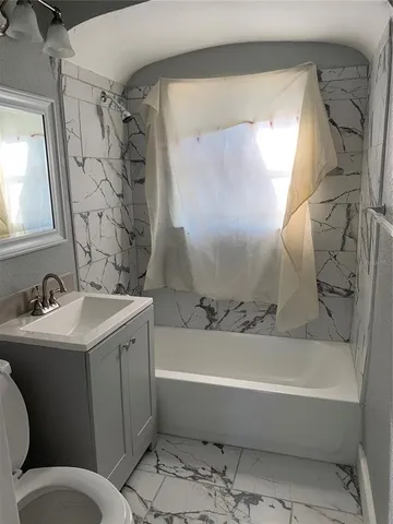 a bathroom with a sink and mirror with bathtub