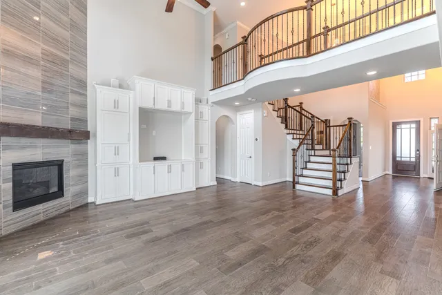 a view of a livingroom with wooden floor staircase and a kitchen space