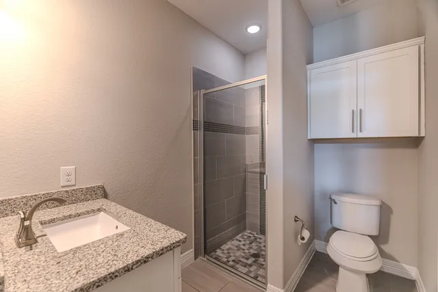 a bathroom with a granite countertop sink and a toilet