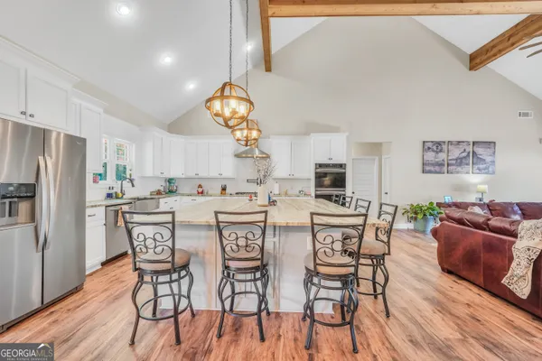 a kitchen with stainless steel appliances kitchen island granite countertop a table chairs and wooden floor