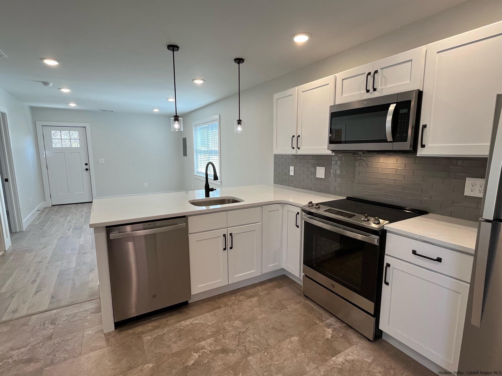 a kitchen with stainless steel appliances white cabinets and stove top oven