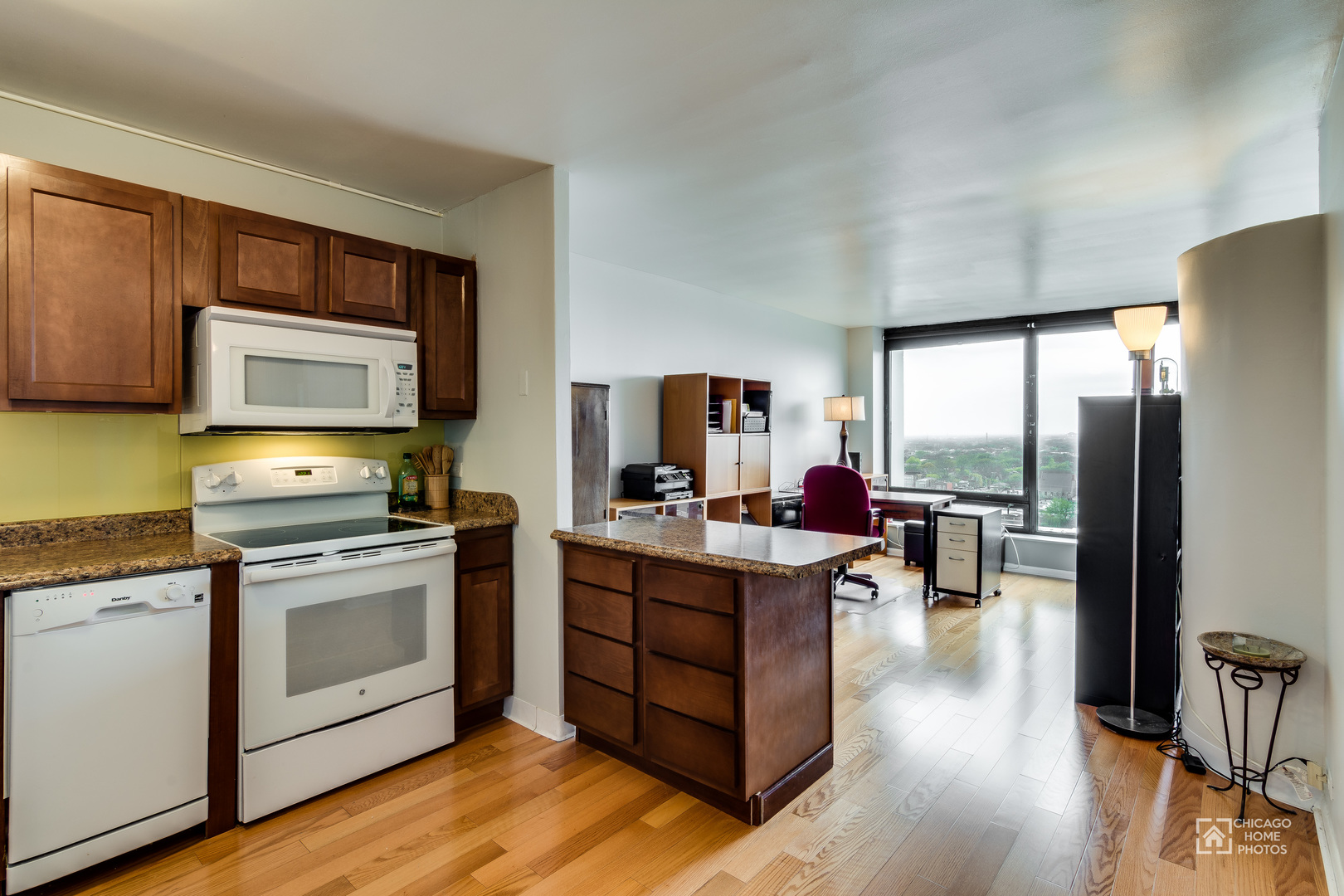 5445 North Sheridan Road, Unit 1809 Chicago, IL 60640 - Photo 9 of 18 a open kitchen with stainless steel appliances granite countertop a stove top oven a refrigerator a dining table and chairs with wooden floor