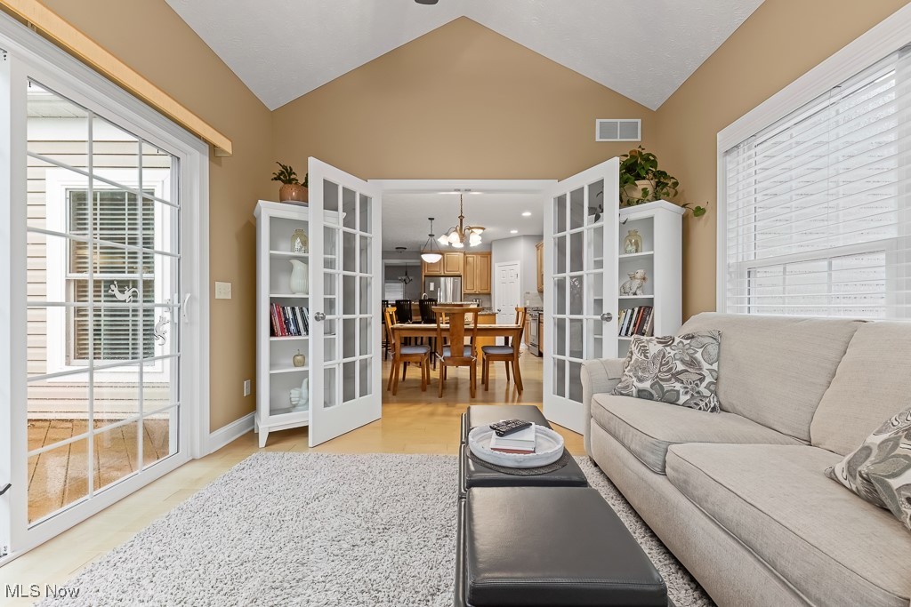 369 Eldridge Road Aurora, OH 44202 - Photo 11 of 50 Living room with french doors, vaulted ceiling, light wood-type flooring, and a chandelier