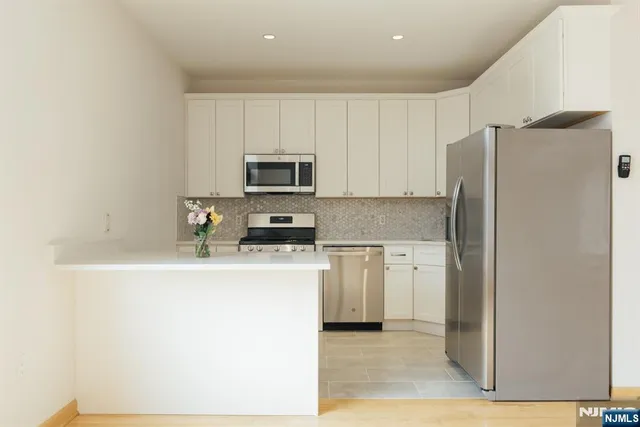 a kitchen with a refrigerator a stove top oven and white cabinets