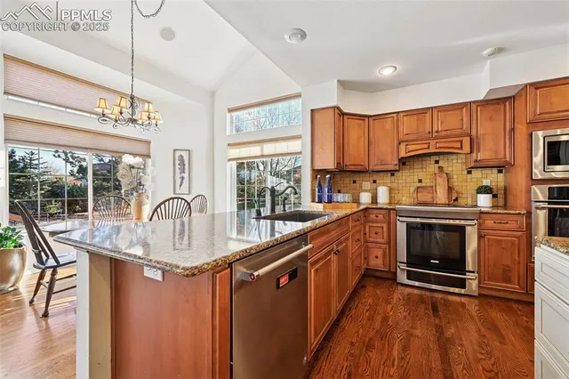 a kitchen with kitchen island granite countertop a stove a sink and wooden cabinets