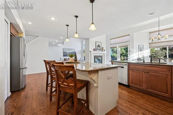 a kitchen with stainless steel appliances a dining table chairs and wooden floor