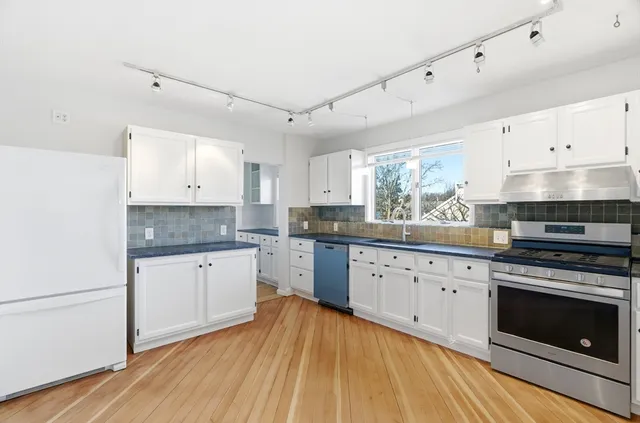 a kitchen with granite countertop white cabinets and white appliances