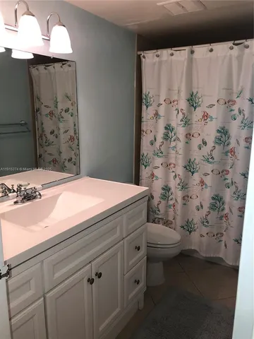 a bathroom with a sink a toilet and shower curtain