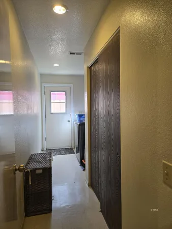 a view of a hallway to a room with wooden floor and windows