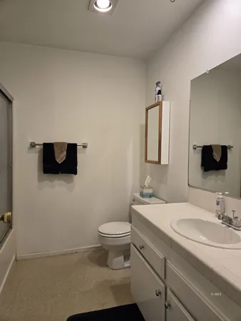 a bathroom with a granite countertop sink a toilet and a mirror