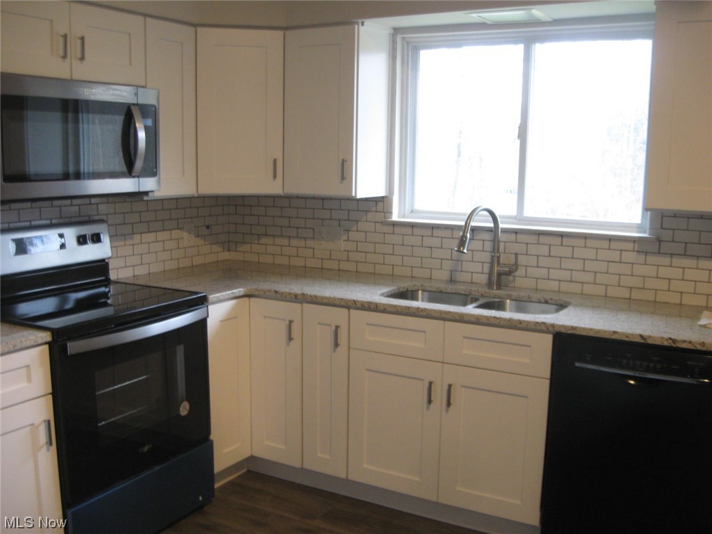 8205 Springview Road Northfield, OH 44067 - Photo 3 of 20 Kitchen featuring dark wood-type flooring, sink, electric range oven, black dishwasher, and white cabinetry