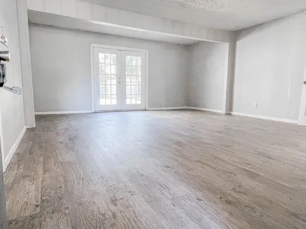 a view of an empty room with wooden floor and window