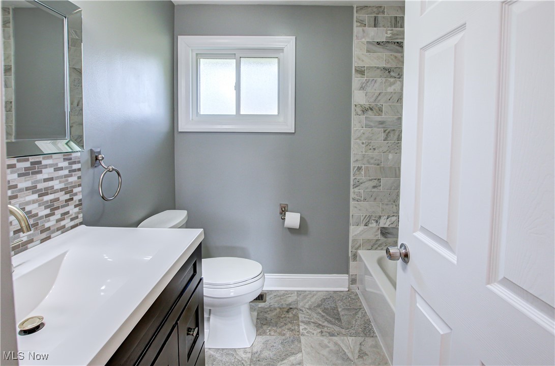 12477 Webster Road Strongsville, OH 44136 - Photo 20 of 40 Full bathroom featuring vanity, toilet, shower combination, and decorative backsplash