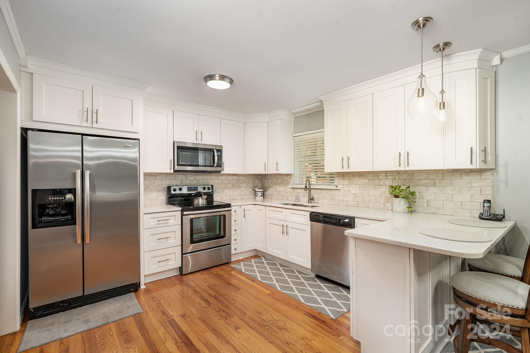 6308 Sunset Circle Charlotte, NC 28216 - Photo 7 of 30 a kitchen with a sink stainless steel appliances and white cabinets