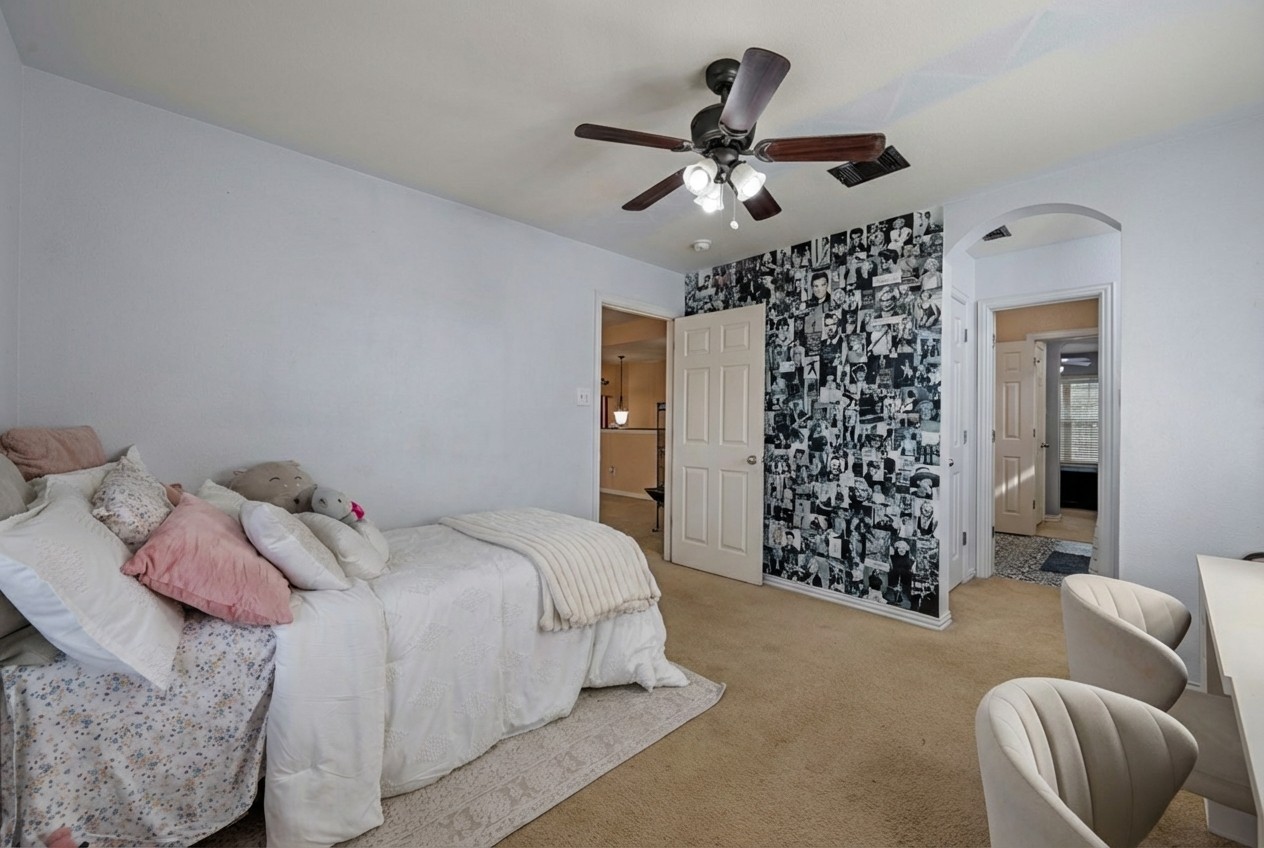 2415 Elkhorn Ranch Road Leander, TX 78641 - Photo 19 of 38 Bedroom featuring arched walkways, a ceiling fan, carpet floors, and wallpapered walls