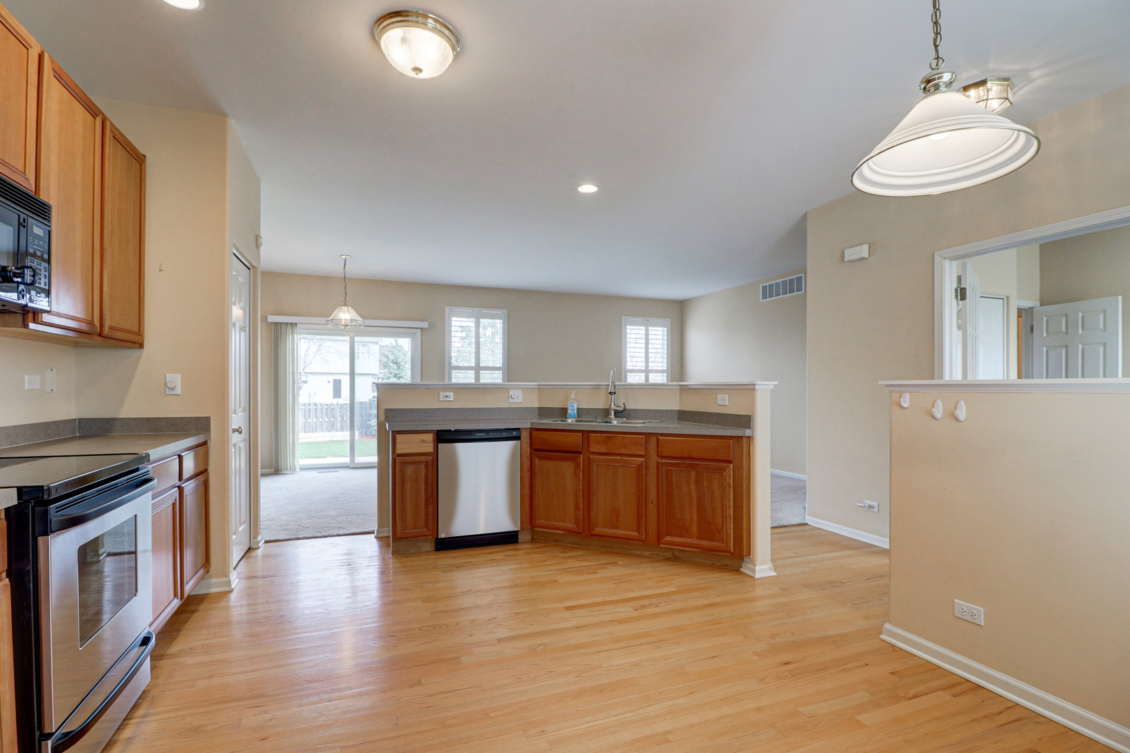 32670 Innetowne Road Lakemoor, IL 60051 - Photo 7 of 25 a kitchen with stainless steel appliances granite countertop a stove a sink dishwasher a refrigerator and a fireplace with wooden floor