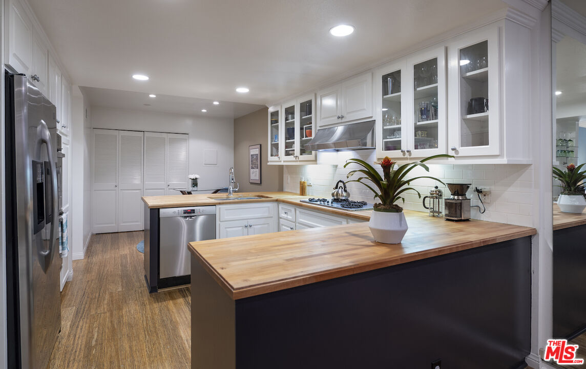 11687 Bellagio Road, Unit 3 Los Angeles, CA 90049 - Photo 16 of 31 a kitchen with stainless steel appliances granite countertop a sink a stove and a refrigerator